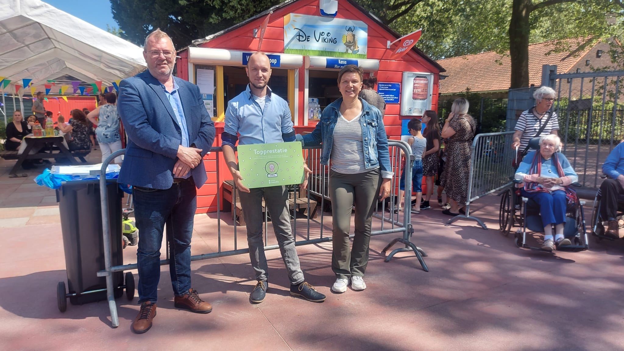 Twee mannen en een vrouw, waarvan een man de topprestatiebadge voeding vast heeft